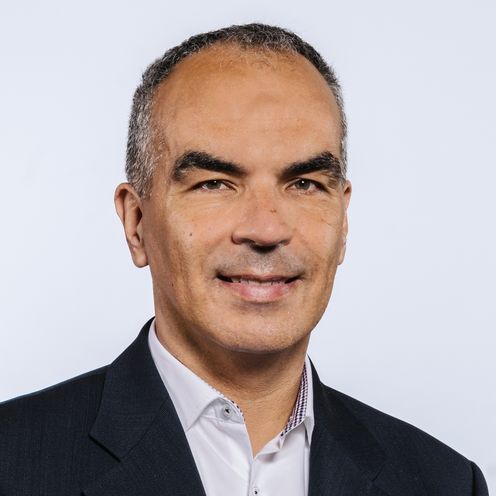 Martin Holi Auf dem Bild ist Martin Holi zu sehen. Er hat kurzes Haar und trägt ein weißes Hemd unter einem dunkel Jacket.