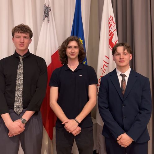 202605 STARS EU Student Board Conference Malta A group photo of three young men. They are standing in front of flags.