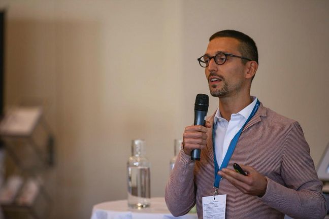 Dr. Giacomo Rossettini Dr. Giacomo Rossettini hält ein Mikrofon in der Hand und spricht in das Mikrofon