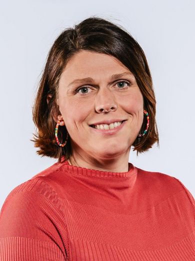 Miona Straatmann Auf dem Bild ist Miona Straatmann zu sehen. Sie hat kinnlanges rotbraunes Haar und trägt ein rotes Kleid.