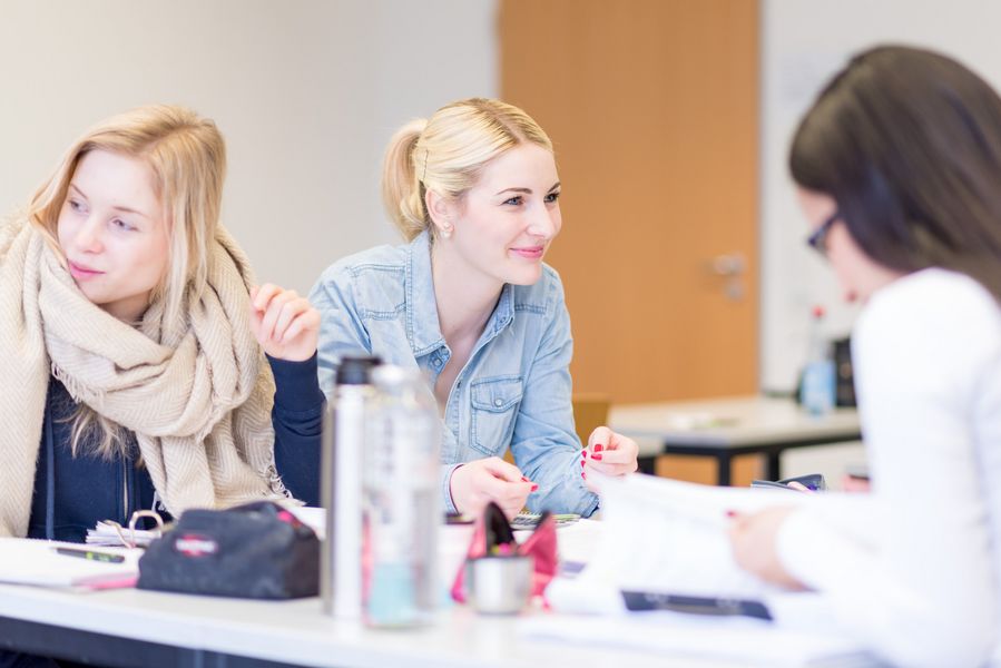 Studierende Studierende sitzen in einem Vorlesungsraum und unterhalten sich.
