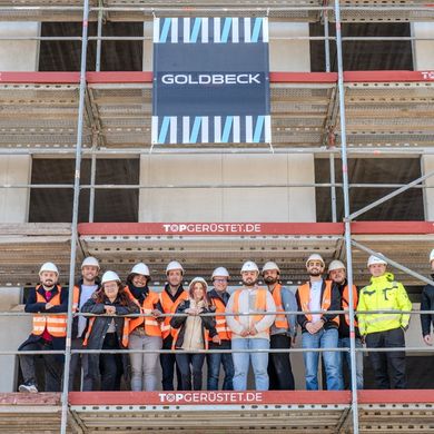 Baustellenbesichtigung im CBL-Modul Gruppe von Menschen steht auf einem Baugerüst vor einem Gebäude.