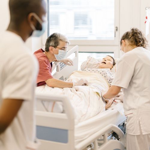 Pflegestudierende üben im mit einer Puppe im Simulationszentrum Pflegestudierende üben an einem Krankenhausbett mit einer Puppe im Simulationszentrum des Studiengangs.