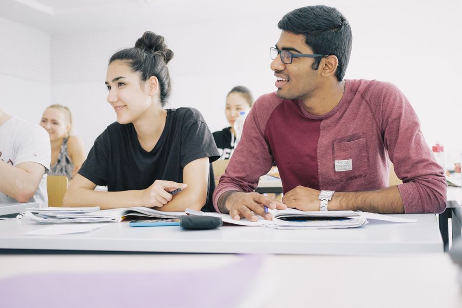 Studierende Studierende sitzen nebeneinander an Tischen in einem Seminarraum.