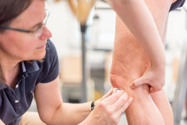 Eine Frau bringt einen Sensor am Knie einer Studentin an, um damit Bewegungen aufzuzeichnen.