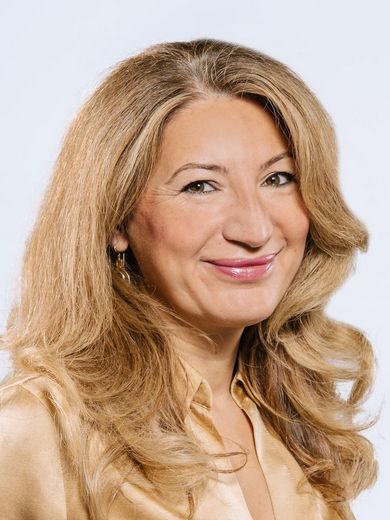 Gonca Efe-Sahantürk Auf dem Bild ist Gonca Efe-Sahantürk zusehen. Sie hat langes, blondes Haar und trägt eine goldene Bluse.