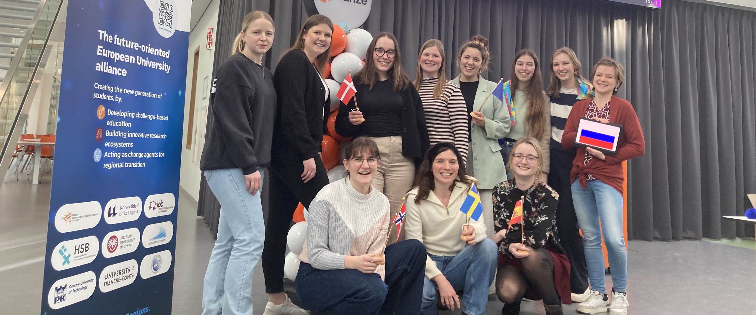 BIP Groningen STARS EU Gruppenbild mit weiblichen Studierenden. Neben ihnen steht ein STARS EU Roll up. Im Hintergrund sieht man einen großen Monitor mit Logos.