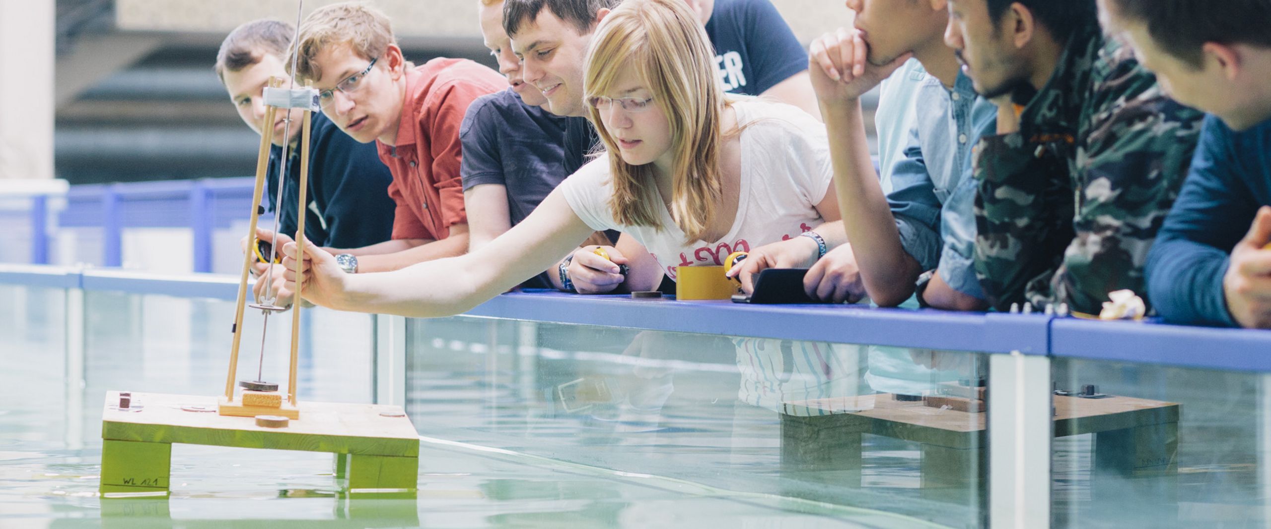 Studierende am Strömungskanal Studierende testen eine schwimmende Konstruktion in einem Wasserbecken.