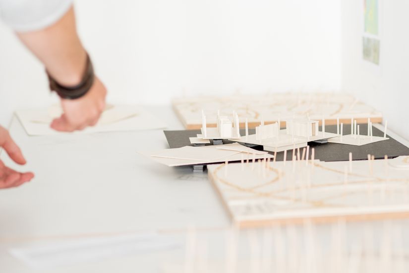 Eine Hand deutet auf architektonische Modelle von Gebäuden. Eine Hand deutet auf architektonische Modelle von Gebäuden.