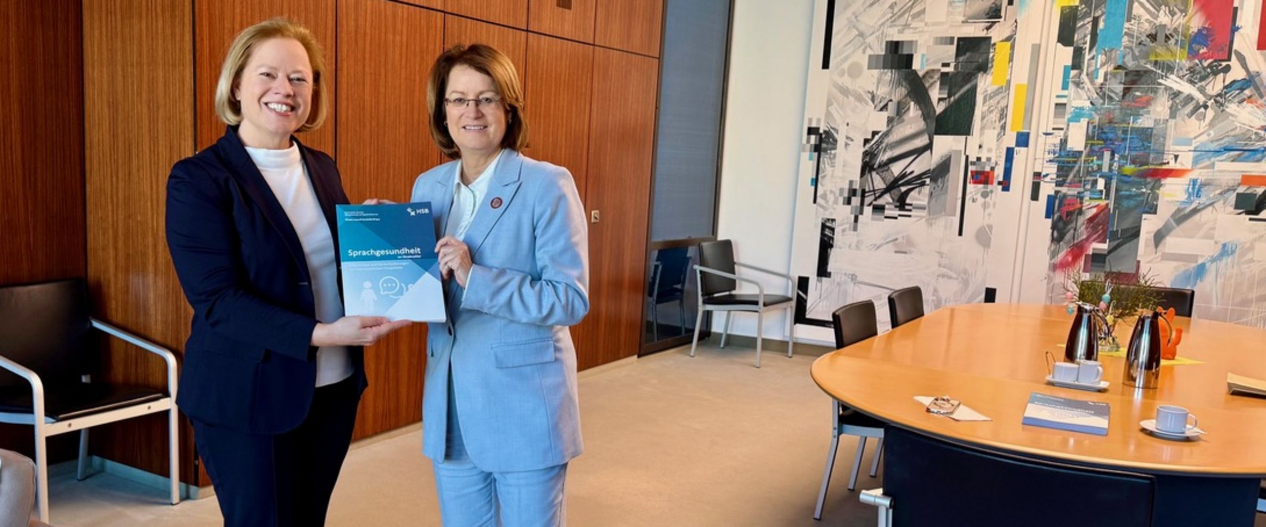 Übergabe Studie Sprachgesundheit Zwei Frauen in einem Büro. Gemeinsam halten sie die Studie in Händen.