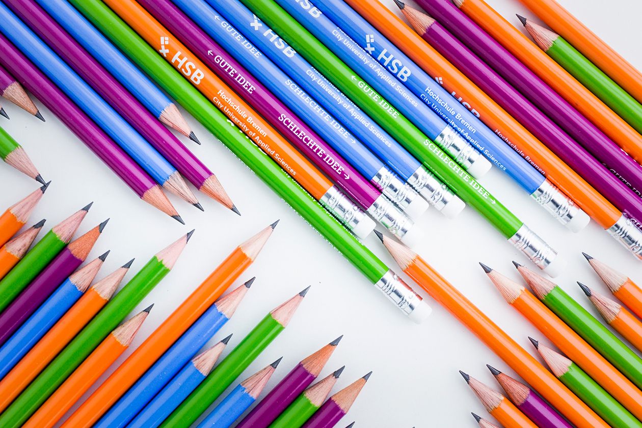 HSB Bleistift Nebeneinander liegen mehrere blaue, grüne, violette und orangene Bleistifte, die das HSB-Logo tragen.