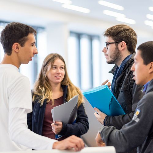 Studierendengruppe Eine Gruppe Studierender mit Unterlagen in der Hand unterhält sich.
