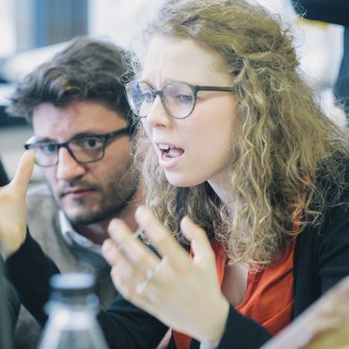 Junge Frau hebt zweifelnd die Hände.