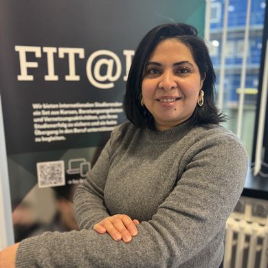 Sana Arousse FIT@HSB Portait einer Frau. Im Hintergrund sieht man ein Roll-up