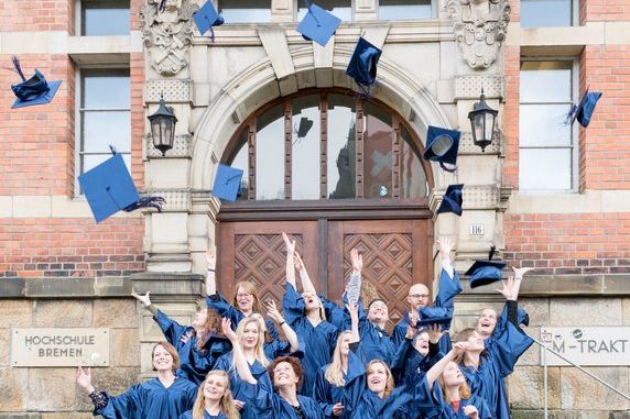 Studierende Abschlussveranstaltung Absolventinnen und Absolventen werfen Hüte in die Höhe