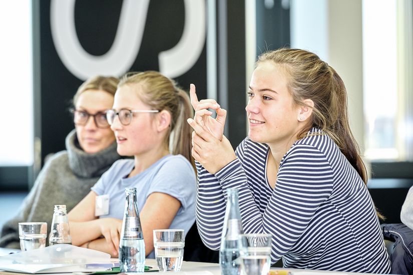 HSB_Mint_Frauen_und_Technik Drei Studentinnen sitzen nebeneinander beim MINT Speed Dating: Frauen und Technik. Eine hebt ihre Hand.