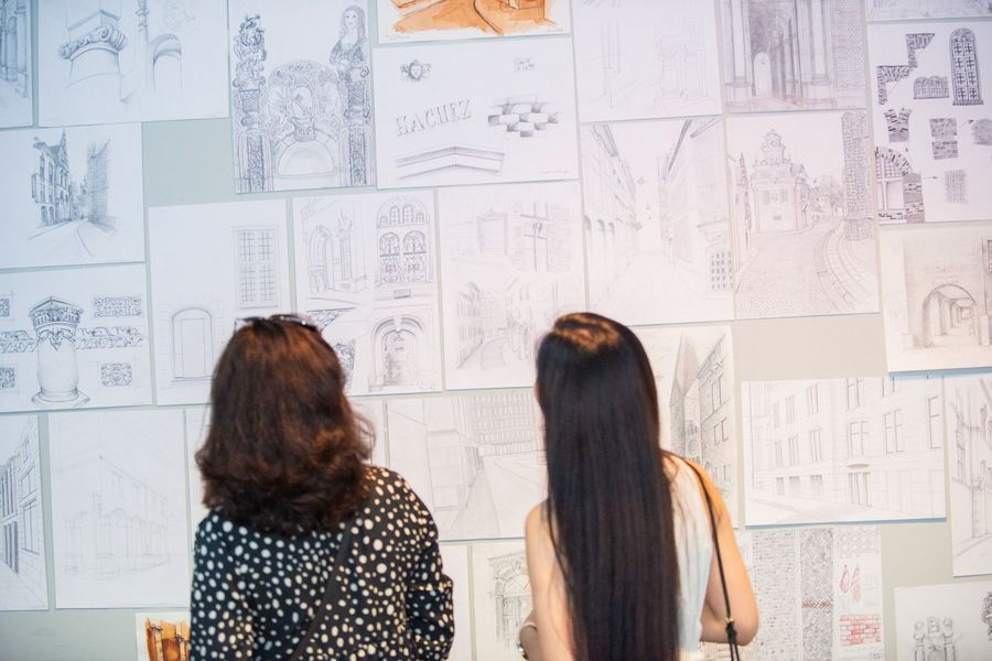 Zwei Frauen betrachten architektonische Skizzen an einer Wand. Zwei Frauen betrachten architektonische Skizzen an einer Wand.