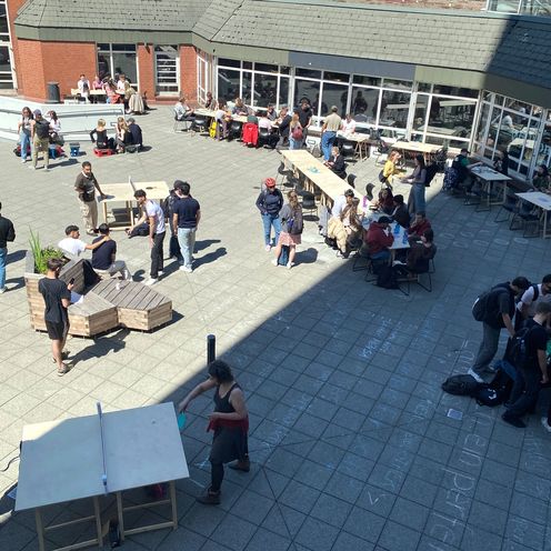 Interspace 2025 Photo from above on the forecourt of a building. People sit and stand there and play ping pong