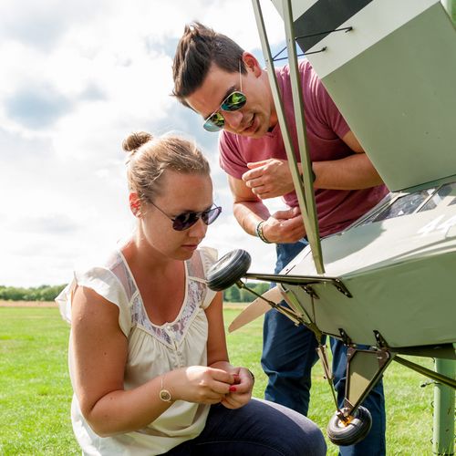 Studierende mit einem Modellflugzeug Studierende arbeiten auf einer Wiese an einem Modellflugzeug
