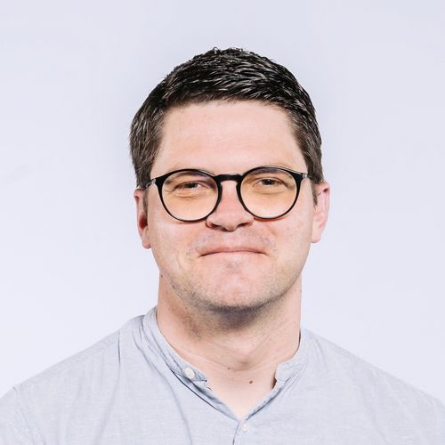 Christian Fieberg Auf dem Bild ist Christian Fieberg zu sehen. Er trägt kurzes schwarzes Haar, eine ründliche Brille und ein hell blaues Hemd.