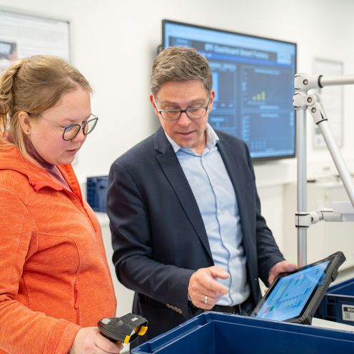 202505_Smart Factory Studentin Prof Junge Frau und Mann schauen auf ein Tablet.