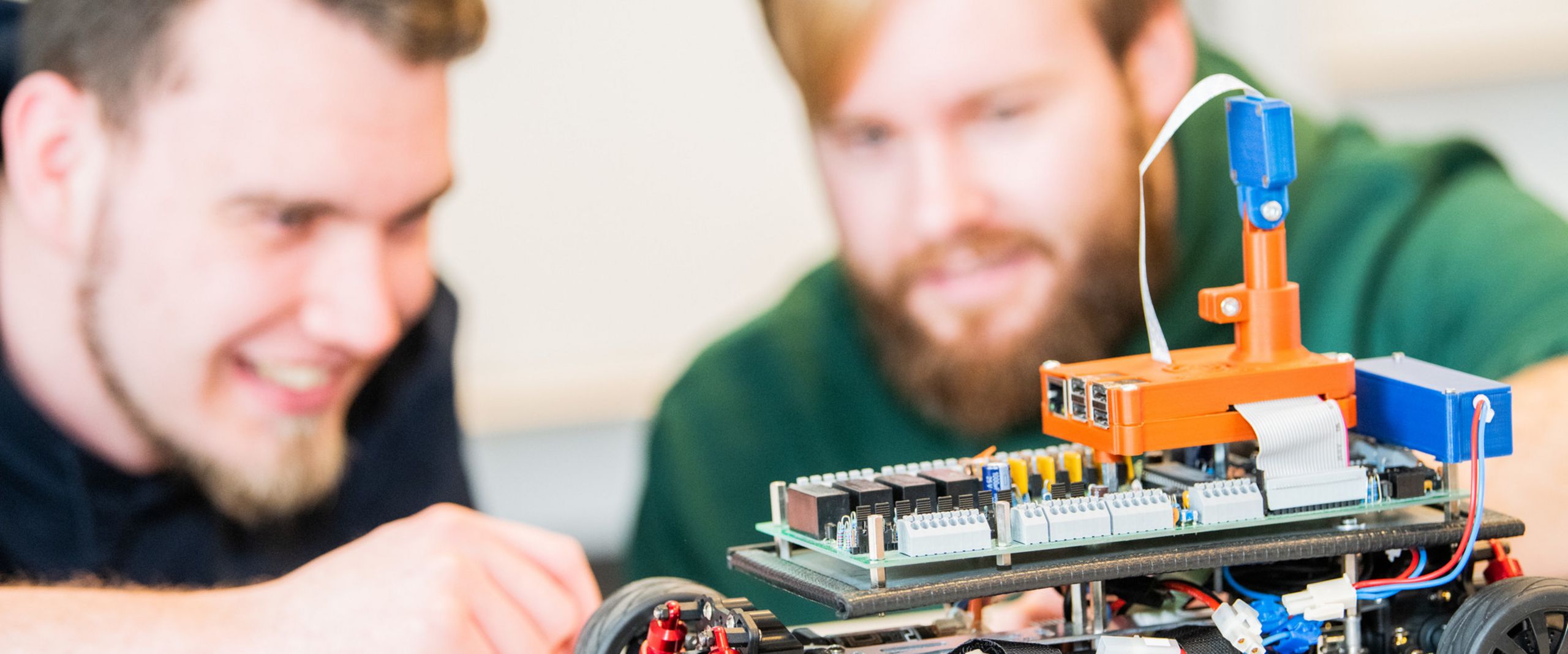 Praxis in der Vorlesung Zwei Studenten betrachten ein elektrisches Modellauto.