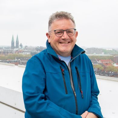 SZHB Jeremy Hookway Mann steht am Geländer und lacht in die Kamera