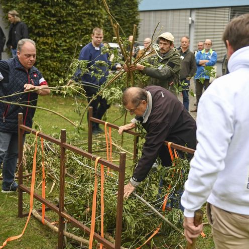 25041_0500_Gesunder See – viele Fische Teilnehmer_und_Prof._Klefoth_buendeln_Totholz Männer stehen im Freien vor Holzkonstrukten