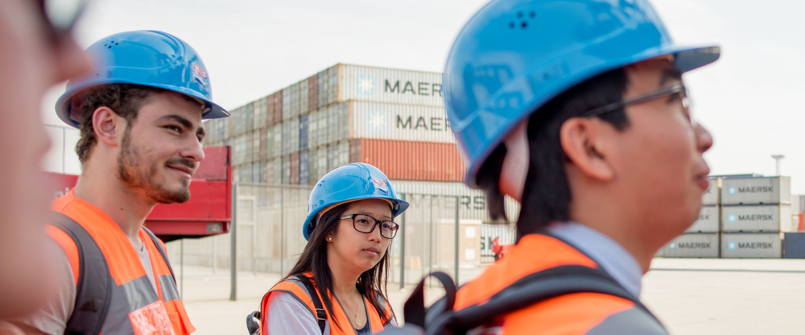 Studierende besichtigen Container Terminal Studierende mit bauen Sicherheitshelmen und orangen Westen besichtigen Container Terminal