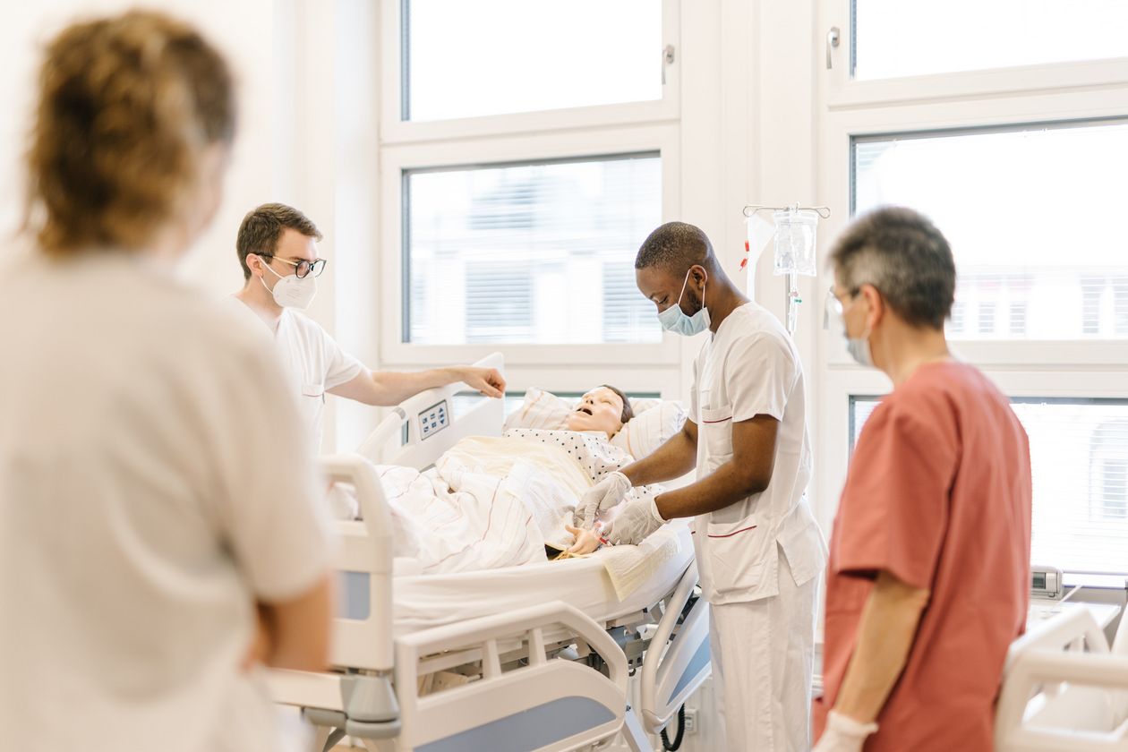 Pflegestudierende im Skills Lab am Brill Pflegestudierende üben an einem Krankenhausbett mit einer Puppe im Simulationszentrum des Studiengangs.
