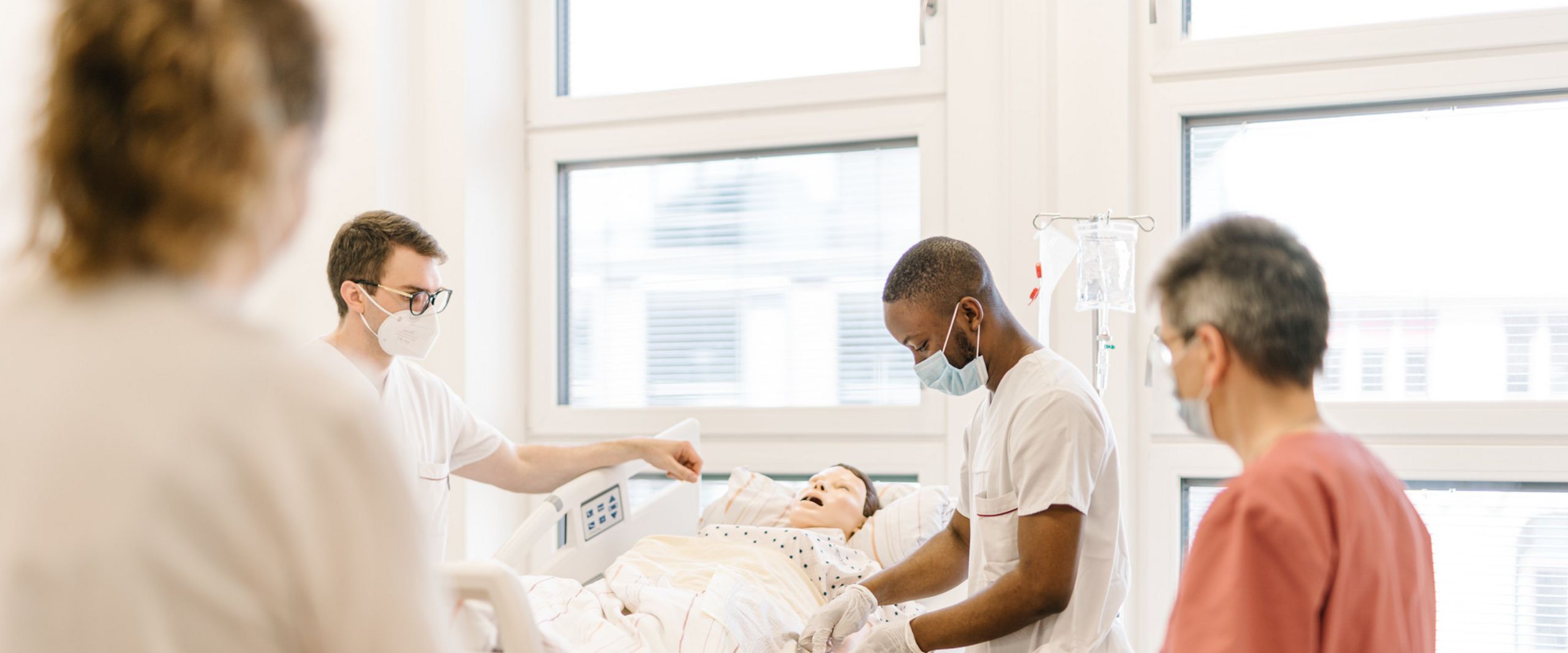 Pflegestudierende im Skills Lab am Brill Pflegestudierende üben an einem Krankenhausbett mit einer Puppe im Simulationszentrum des Studiengangs.