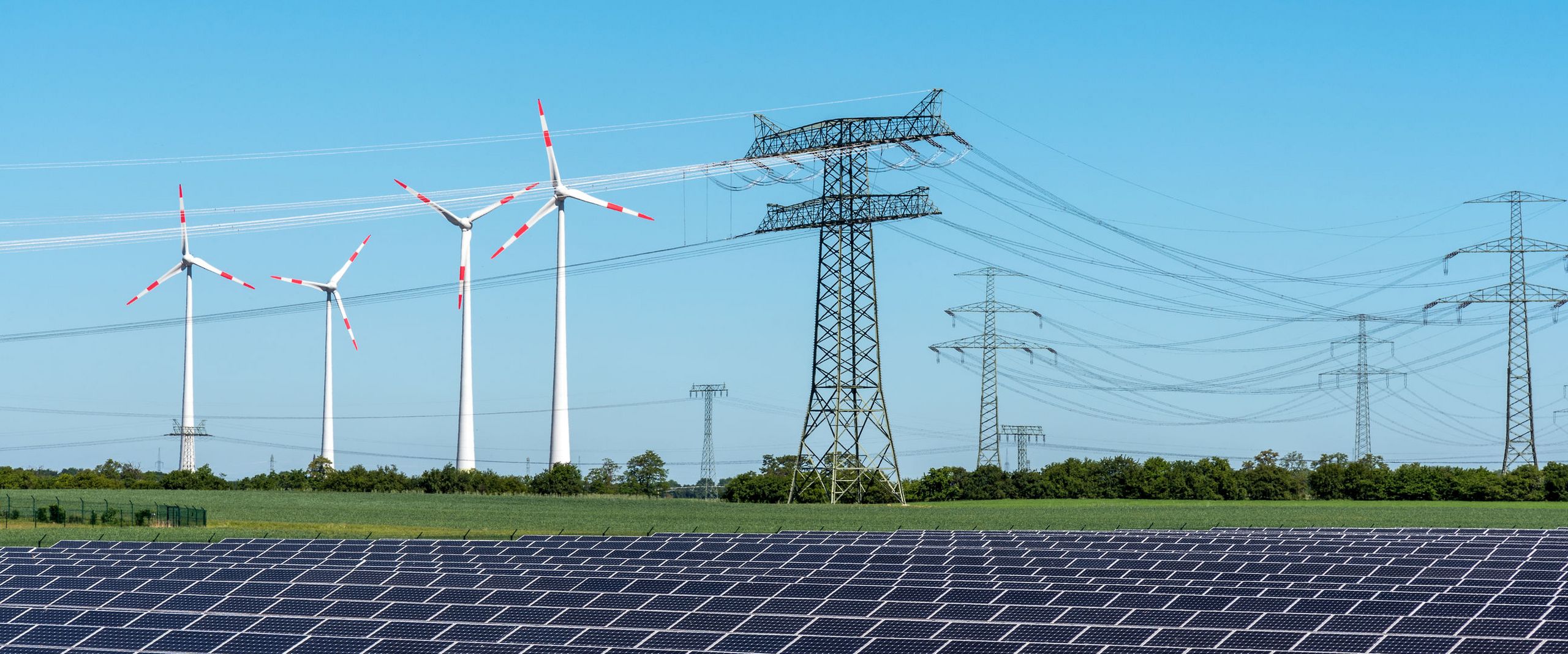 Landschaft mit Energiequellen In einer Landschaft stehen Windräder, Solaranlagen und Strommasten nebeneinander