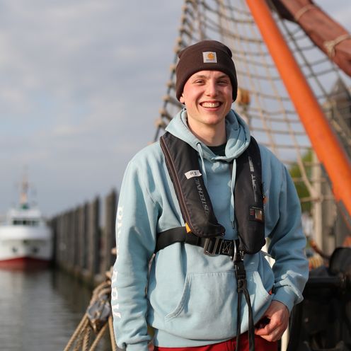 Louis Lammers Franzius Projekt 2026 Junger Mann mit Schwimmweste, Pullover und Mütze auf einem Schiff.